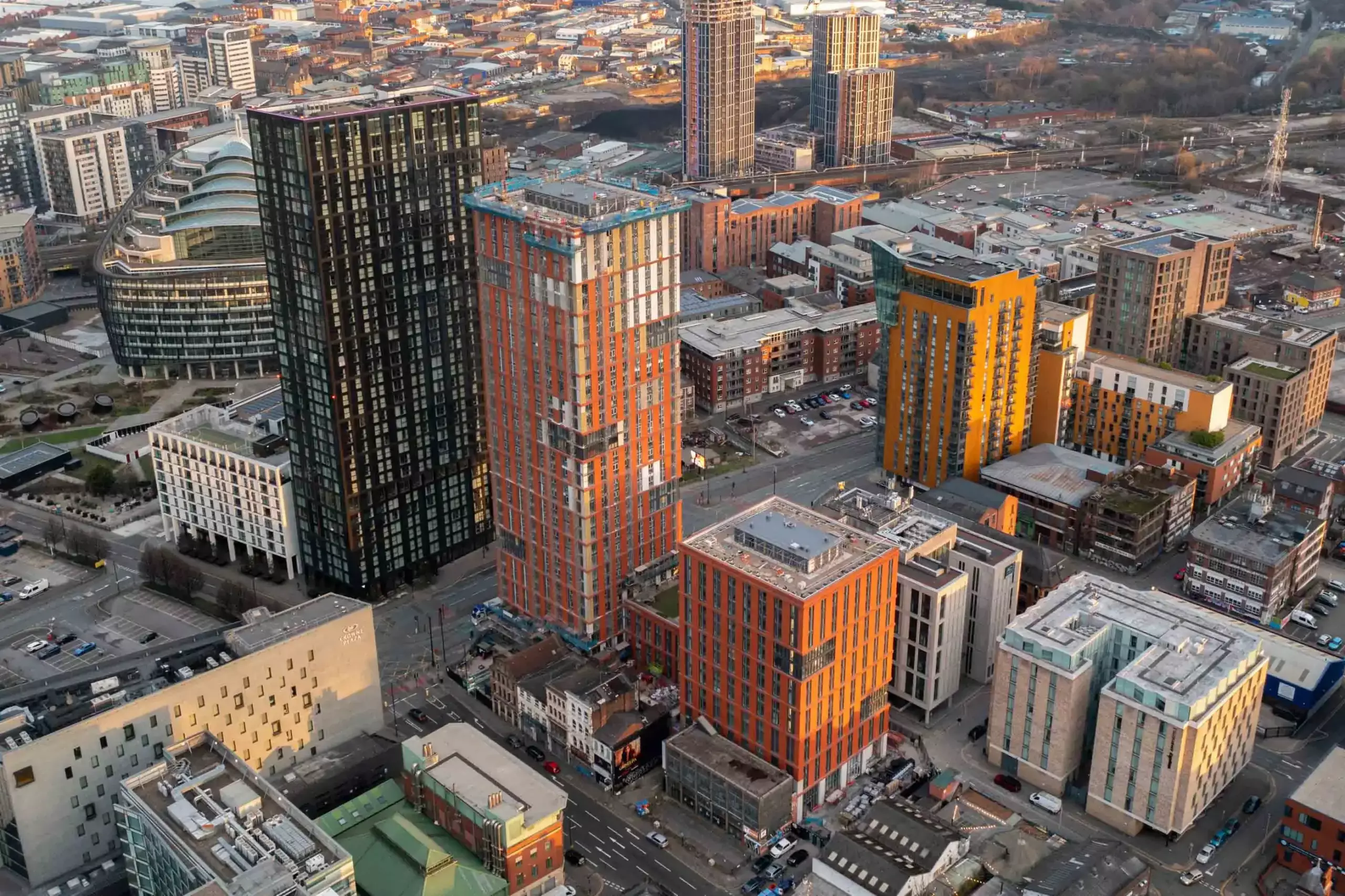 Aerial drone progress reporting of a tower block being built in Manchester during later stages nearing completion early morning red building