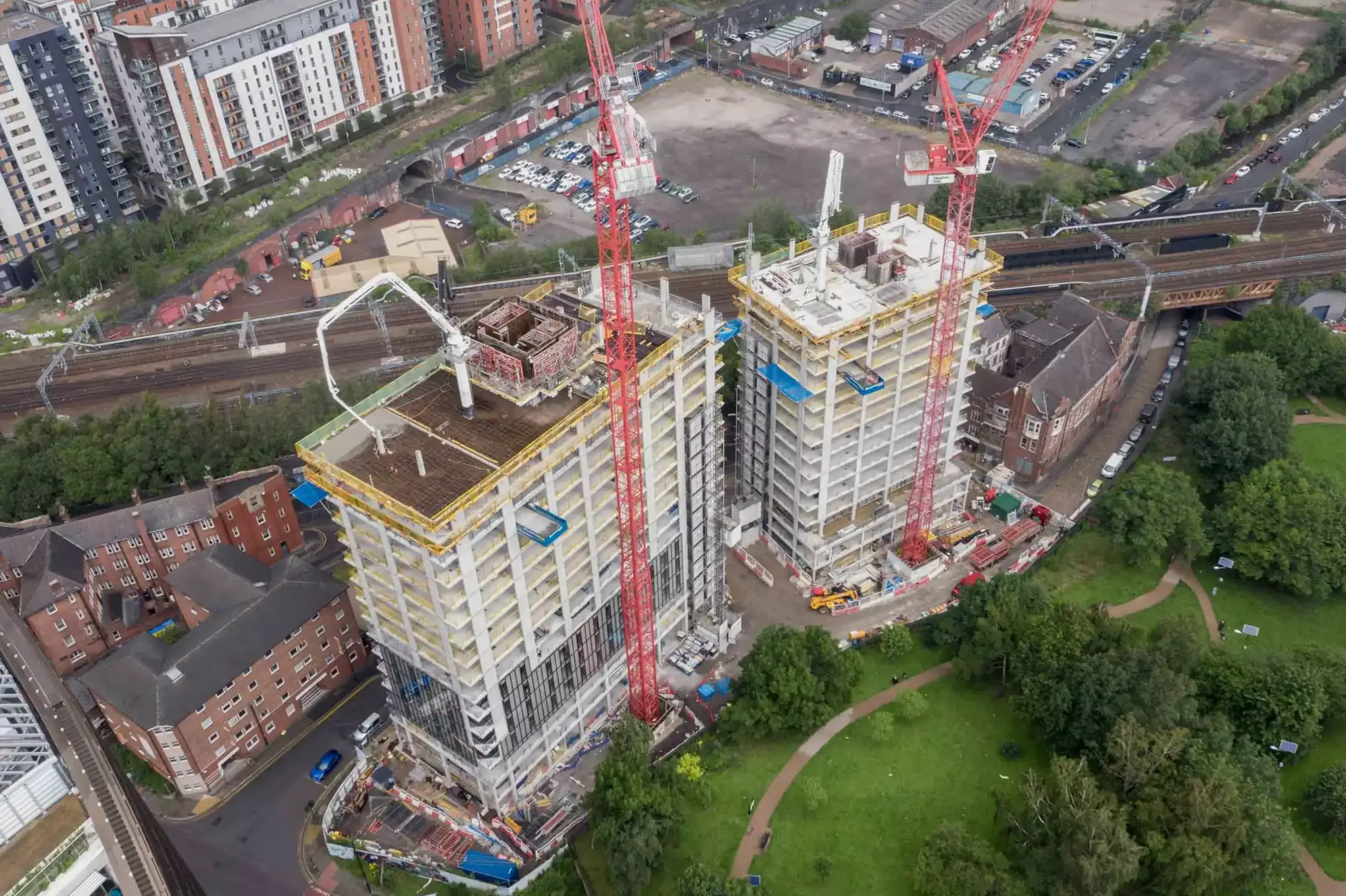 Aerial drone progress reporting of two tower blocks in Manchester next to a railway early in the build stage
