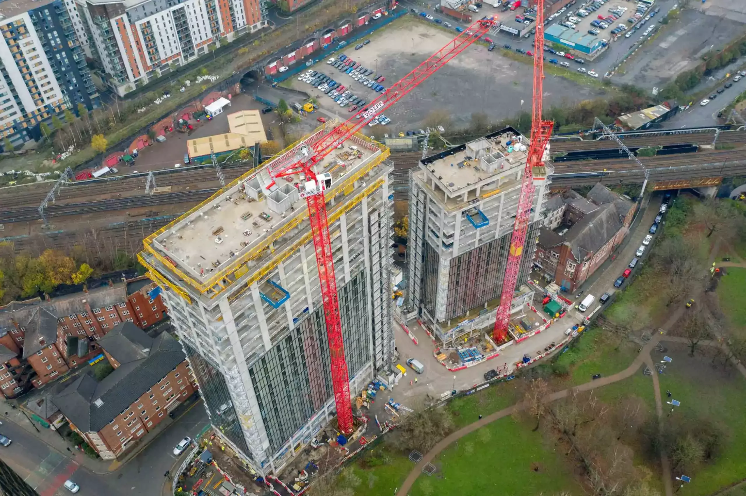 Aerial drone progress reporting of two tower blocks in Manchester next to a railway halfway through development